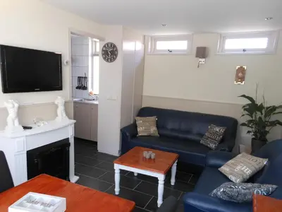 a living room with a blue couch and a tv at Brugman in Egmond aan Zee