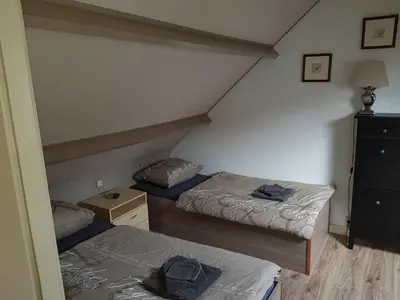 a room with two beds and a dresser in a attic at Brugman in Egmond aan Zee