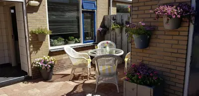 a patio with a table and chairs and flowers at Brugman in Egmond aan Zee