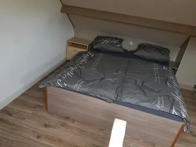 a bed in a small room with a wooden floor at Brugman in Egmond aan Zee