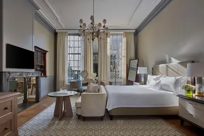 a bedroom with a large white bed and a chandelier at Waldorf Astoria Amsterdam in Amsterdam