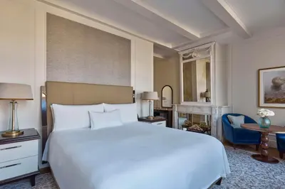 a bedroom with a white bed and a blue chair at Waldorf Astoria Amsterdam in Amsterdam