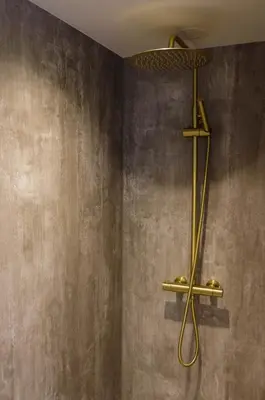 a shower with a gold shower head on a wall at Hotel de Duif Lisse - Keukenhof in Lisse