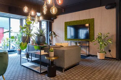 a living room with a couch and a tv and plants at Hotel de Duif Lisse - Keukenhof in Lisse