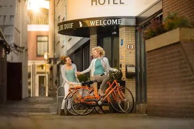 two women standing next to a bike on a street at Hotel de Duif Lisse - Keukenhof in Lisse