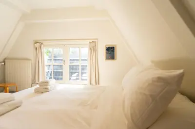 a bedroom with a white bed with a window at hotel calisto in Amsterdam