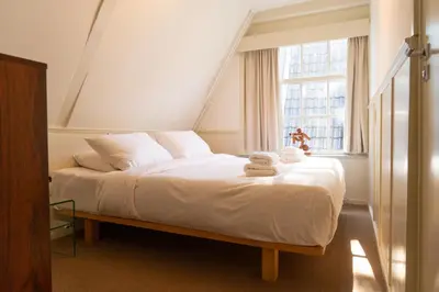 a bedroom with a bed with white sheets and a window at hotel calisto in Amsterdam