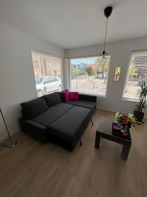 a living room with a black couch and a table at Duinroos aan Zee in Egmond aan Zee