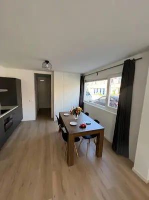 a living room with a table and a kitchen at Duinroos aan Zee in Egmond aan Zee