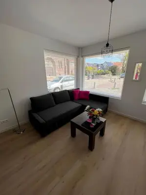 a living room with a black couch and a table at Duinroos aan Zee in Egmond aan Zee
