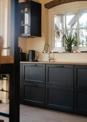 a kitchen with black cabinets and a sink and a window at Huisje Hartenlust in Bodegraven