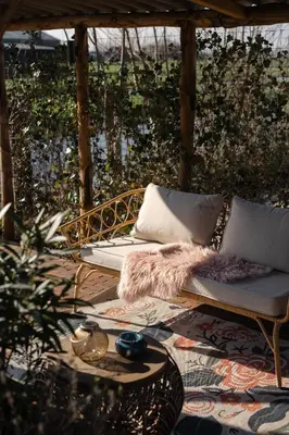 a couch on a patio with a table at Huisje Hartenlust in Bodegraven