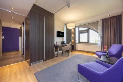 a living room with purple furniture and a dining room at Fletcher Hotel-Restaurant Nieuwegein-Utrecht in Nieuwegein