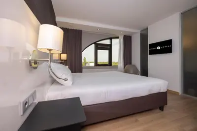 a bedroom with a large white bed and a window at Fletcher Hotel-Restaurant Nieuwegein-Utrecht in Nieuwegein