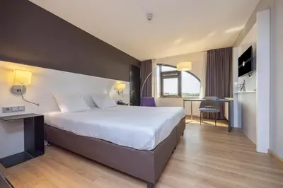 a hotel room with a large bed and a desk at Fletcher Hotel-Restaurant Nieuwegein-Utrecht in Nieuwegein