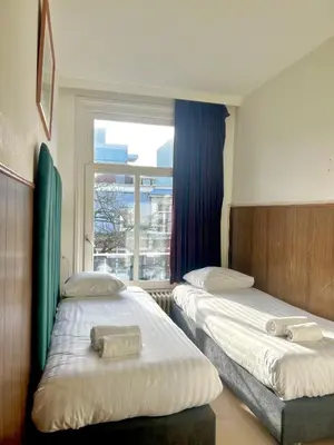 two beds in a room with a window at Hotel Kap City Centre in Amsterdam
