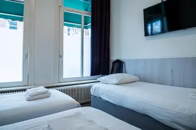 two beds in a room with two windows at Hotel Kap City Centre in Amsterdam