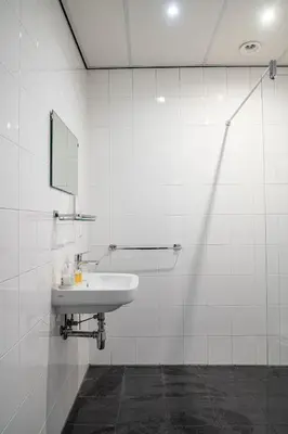 a white tiled bathroom with a sink and a mirror at Hotel Kap City Centre in Amsterdam
