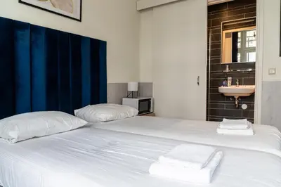 a white bed with two pillows and a sink at Hotel Kap City Centre in Amsterdam