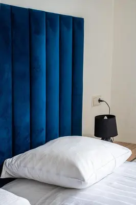 a bed with a blue headboard and a white pillow at Hotel Kap City Centre in Amsterdam