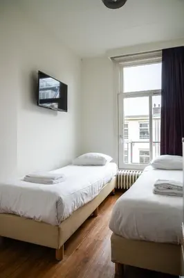 two beds in a room with a window at Hotel Kap City Centre in Amsterdam
