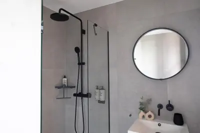 a bathroom with a shower with a sink and a mirror at Bob W Amsterdam Noord in Amsterdam