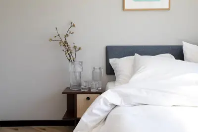 a bed with white sheets and a vase on a table at Bob W Amsterdam Noord in Amsterdam