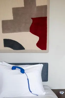 a painting above a bed with a blue cord on it at Bob W Amsterdam Noord in Amsterdam