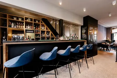 a bar with blue stools in a restaurant at Catalonia Vondel Amsterdam in Amsterdam