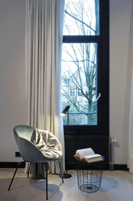 a living room with a chair and a window at Catalonia Vondel Amsterdam in Amsterdam