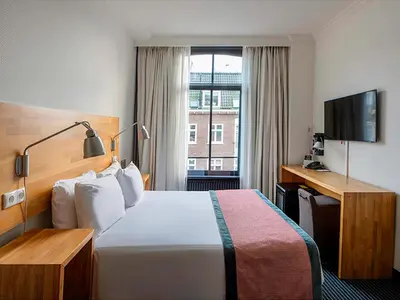 a hotel room with a bed and a television at Catalonia Vondel Amsterdam in Amsterdam