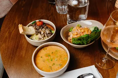 a wooden table with three bowls of food on it at Strandhotel Camperduin in Schoorl