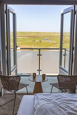 a room with a bed and two chairs and a table at Strandhotel Camperduin in Schoorl