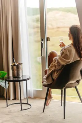 a woman sitting in a chair holding a glass of wine at Strandhotel Camperduin in Schoorl