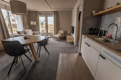 a kitchen with a table and a living room at Strandhotel Camperduin in Schoorl