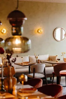 a restaurant with tables and couches in a room at Strandhotel Camperduin in Schoorl