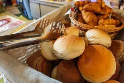 a bin filled with buns and forks and pastries at Hotel De Looier in Amsterdam