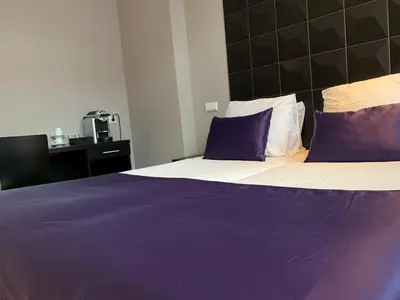 a bedroom with a large bed with purple sheets and pillows at Hotel De Looier in Amsterdam