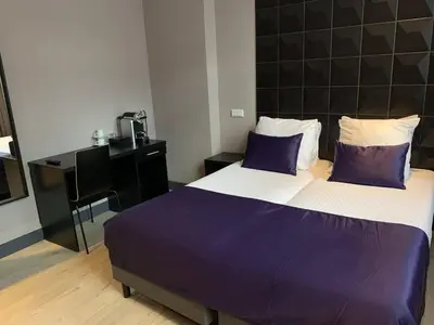 a bedroom with a bed with purple sheets and a desk at Hotel De Looier in Amsterdam