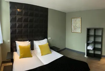 a bedroom with a large bed with yellow pillows at Hotel De Looier in Amsterdam