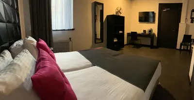 a bedroom with a large white bed with red pillows at Hotel De Looier in Amsterdam