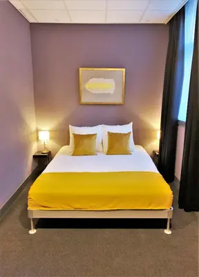 a bedroom with a large yellow bed with yellow pillows at Hotel De Looier in Amsterdam