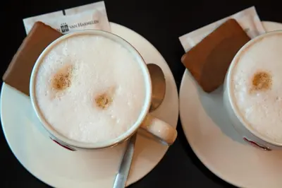 two cups of cappuccinos on plates on a table at Het Wapen van Harmelen in Harmelen