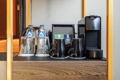a shelf with bottles and glasses and a coffee maker at Hotel Die Port van Cleve in Amsterdam