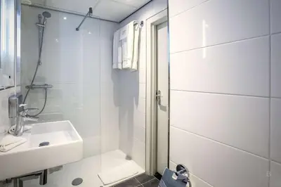 a white bathroom with a shower and a sink at Hotel Die Port van Cleve in Amsterdam