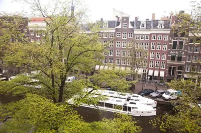 a boat is docked in a river with buildings at Hotel Estheréa in Amsterdam