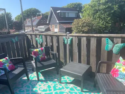 a patio with chairs and butterflies on a fence at Zee En Meer in Egmond aan Zee