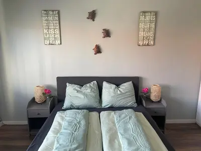 a bedroom with a bed with two tables and two pictures on the wall at Zee En Meer in Egmond aan Zee