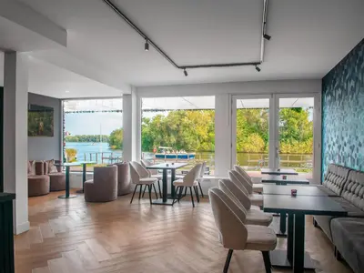 a living room with tables and chairs and a couch at Amsterdam Lake Hotel in Badhoevedorp
