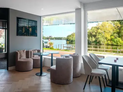 a room with tables and chairs and a large window at Amsterdam Lake Hotel in Badhoevedorp
